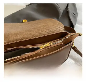 Detail view of the woven flap texture and smooth gold zipper on a brown crossbody bag