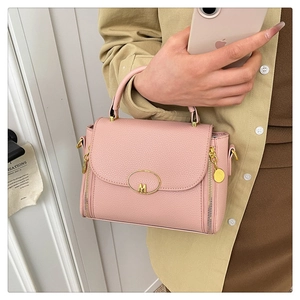 Detail of pink lychee textured leather bag featuring golden M buckle and side dual zippers