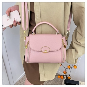 On-body shot of a pink lychee-patterned crossbody bag with gold M-logo and side zippers