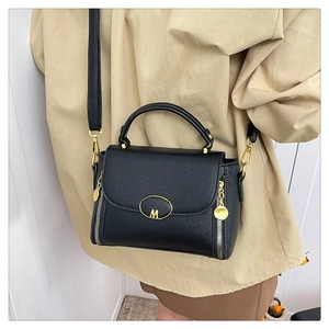 Close-up of black lychee grain leather handbag featuring gold hardware and M-logo detail
