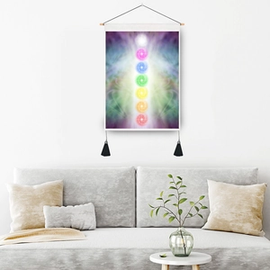 Vertical seven chakra tapestry with wooden hanger and black tassels on white wall