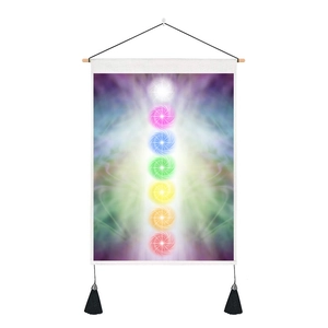 Detail of seven chakra tapestry with wooden rod and black tassels on white fabric