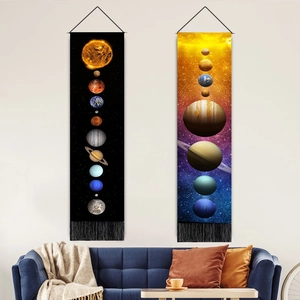 Solar system planet wall tapestries with tassels hanging above a modern living room sofa
