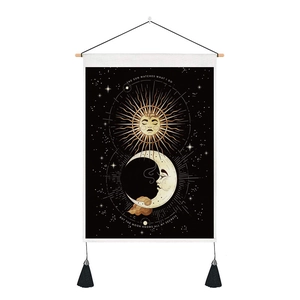 Detail of fabric wall tapestry with sun moon pattern, wooden rod and black tassels
