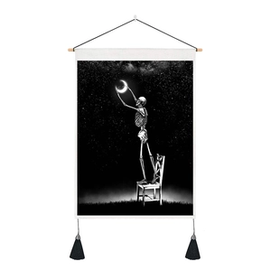 Detail of celestial skull tapestry with moon artwork, wooden rod, and black tassels