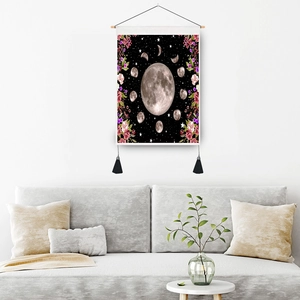 Floral moon phase wall tapestry with wooden rod and black tassels in a modern living room