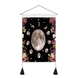 Detail of moon phase tapestry with floral borders, wooden rod, and black tassels