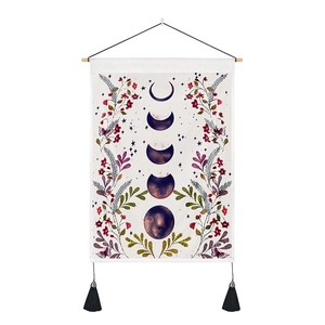 Detail of lunar phase tapestry with floral patterns, wooden rod, and black tassels