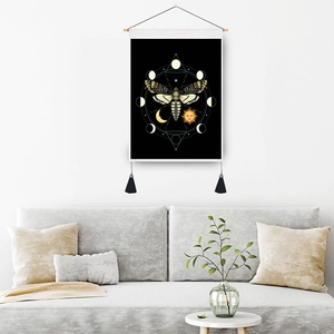 Artistic butterfly wall hanging with moon phases and tassels on a grey living room wall