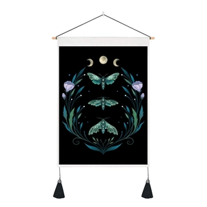 Detail of butterfly wall hanging with moon phases and tassels on black fabric
