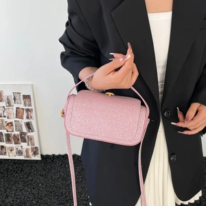 Sac boîte rose scintillant avec boucle dorée porté par un mannequin au style épuré