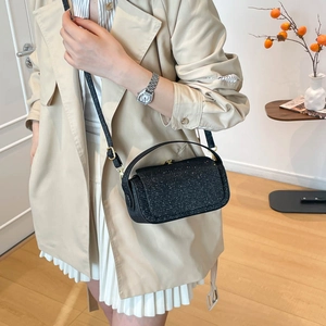 Sac bandoulière pailleté noir avec boucle dorée porté avec un trench beige chic