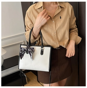 Detail of embossed ivory tote bag with black leather trim and geometric silk scarf decoration