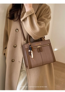 Detail der Retro-Handtasche mit Fischgrätmuster, Holzperlenanhänger und Ledergriff