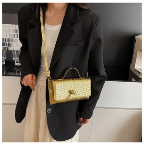 Detail of gold woven texture handbag featuring a modern metallic knot clasp decoration