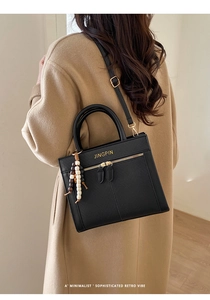 Seitenansicht des Modells mit schwarzer Ledertasche und dekorativem Perlenanhänger