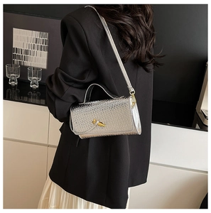 Silver woven shoulder bag with a gold decorative clasp and long adjustable strap