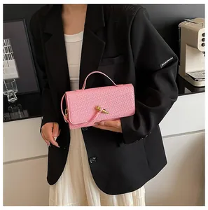 Detailed view of pink woven leather texture with decorative gold knot clasp on handbag