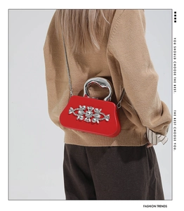 Detail of red rhinestone evening bag with silver metal handle and chain shoulder strap