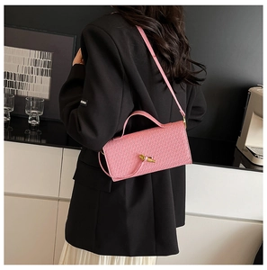 Detail of pink woven baguette bag with a unique gold sculptural twist-lock and slim strap
