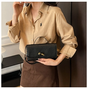 Detailed view of black woven texture bag with an elegant golden knot buckle closure