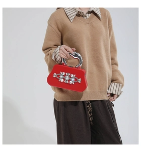 Close-up of red evening bag with silver sculptural handle and sparkling crystal flower detail