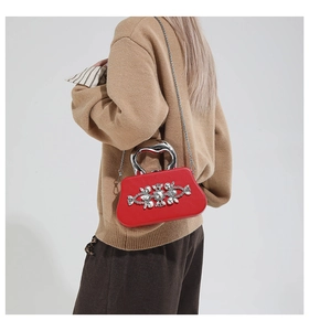 Macro view of red evening clutch featuring crystal floral accents and heart handle