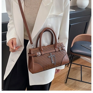 Detail of woven brown leather texture and silver cross hardware on the tote bag
