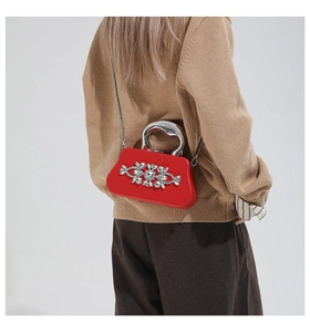 Detail of red rhinestone evening bag with silver metal handle and chain strap