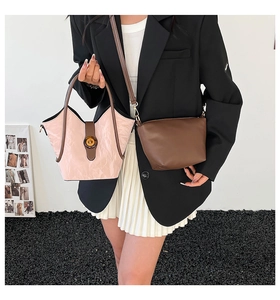 Detail of pink pleated bucket bag and brown crossbody bag shown on a fashion model