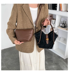 Detail of a brown smooth crossbody bag and a black pleated handbag with amber buckle