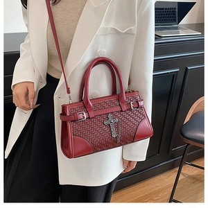 Detail of burgundy woven texture tote bag featuring a vintage cross metal pendant and strap