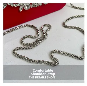 Detailed close-up of the silver woven metal chain strap on a red rhinestone evening bag