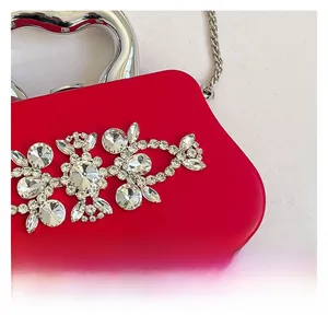 Detailed macro view of red evening bag with rhinestone flowers and heart handle