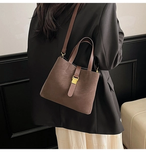 Detail of dark brown bucket bag with gold square buckle and adjustable shoulder strap