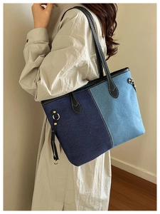 Détail du sac cabas en denim contrasté avec anses en cuir et attache métallique en forme de D