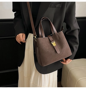 Brown faux suede bucket bag with gold hardware shown on model in a modern interior