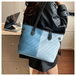 Détail du sac cabas en denim bicolore avec anses en cuir sur un mannequin