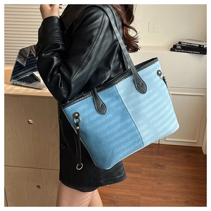 Detail of large denim patchwork tote bag with striped texture and golden hardware