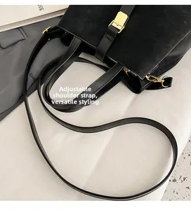 Detail of adjustable strap and golden hardware on a black textured leather bucket bag