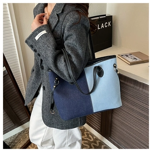 Détail d'un grand sac cabas en denim avec blocs de couleur bleus et anses en cuir noir