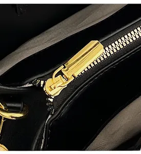 Detailed macro view of smooth gold zipper hardware on a black leather handbag