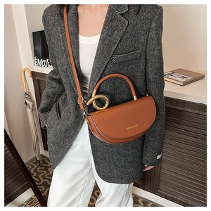 Detail of caramel saddle bag with gold twisted metal handle and adjustable crossbody strap