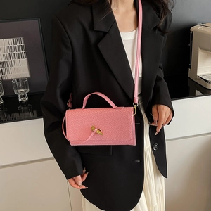 Pink woven baguette crossbody bag with gold twist lock shown on a female model