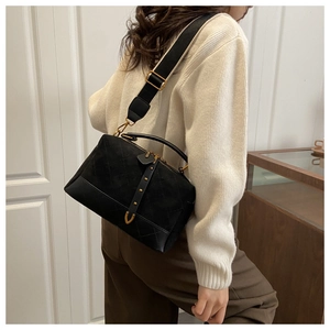 Detail of black suede crossbody bag with diamond quilting and gold-tone hardware