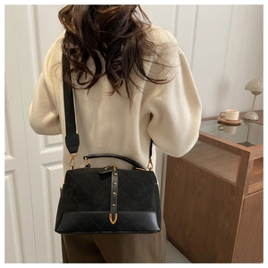 Detail of vintage black suede crossbody bag with rhombus stitching and gold studs on strap