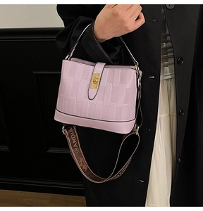 Detail of light purple bucket bag with woven texture, gold lock, and patterned strap