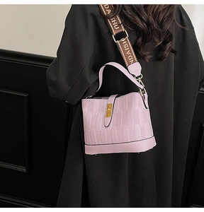 Detailed close-up of purple bucket bag with woven texture and gold twist lock clasp