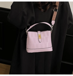 Detail view of purple bucket bag with embossed texture and branded webbed shoulder strap