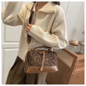 Detail of leopard print suede crossbody bag with gold hardware and wide woven strap